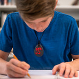 Boy Wearing the Munchables Dragon Chew Necklace while doing schoolwork.