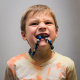 Boy gnawing on anxiety necklace. In mouth.