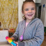 Girl plays with round pop it. Also wears Munchables Unicorn Chew Necklace.