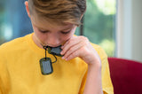 Boy chewing on green camo dog tag chewelry in Canada