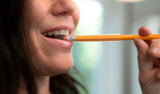 Woman chews on clear chewable pencil topper