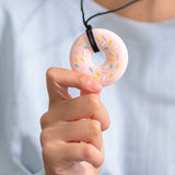 Adult holding pink donut chewable jewelry.