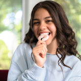 Young adult women chewing on pink donut chewelry.