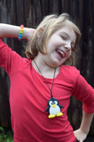Munchables Penguin Chew Necklace being chewed on by girl. Doesn't picture beads that come standard.
