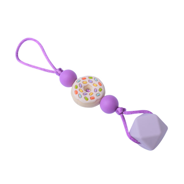 Chewelry that attaches to jacket or sweater. Features silicone donut bead with sprinkles and large purple silicone bead at base.