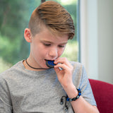 Boy chews on navy blue ninja star chewelry. Also wears Munchables navy camo chew bracelet.