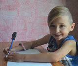 Boy writes with pencil that has the charcoal robot chewing pencil topper