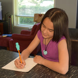 Girl uses pencil with aqua robot chewable pencil topper