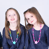 Two girls wearing Munchables Starlight Chew Necklaces.